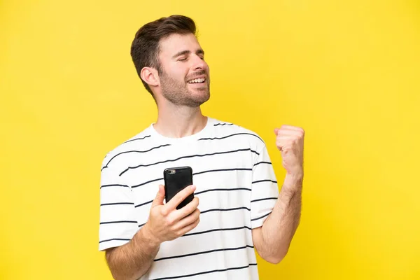 Young Caucasian Man Isolated Yellow Background Phone Victory Position — Stock Photo, Image