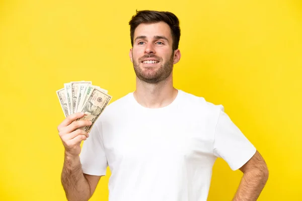 Jonge Kaukasische Man Neemt Veel Geld Geïsoleerd Gele Achtergrond Poseren — Stockfoto