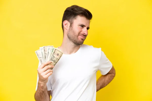 Joven Hombre Caucásico Tomando Mucho Dinero Aislado Sobre Fondo Amarillo — Foto de Stock