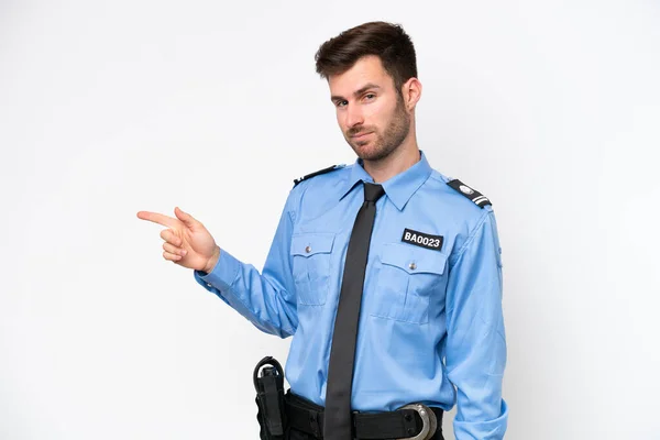 Young police caucasian man isolated on white background pointing finger to the side
