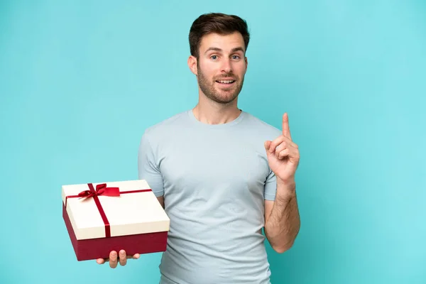 Young Caucasian Man Holding Gift Isolated Blue Background Pointing Great — Stock Photo, Image
