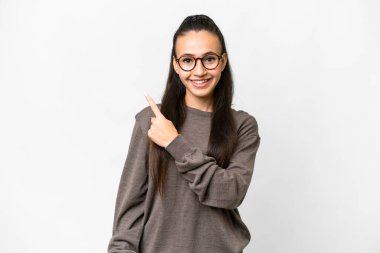 İzole edilmiş beyaz arka planı olan genç bir Arap kadın bir ürünü sunmak için kenarı işaret ediyor.