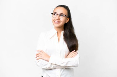 İzole edilmiş beyaz arka planı olan genç bir Arap kadın gülümserken yukarı bakıyor.