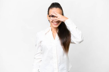 İzole edilmiş beyaz arka planda genç bir Arap kadın. Gözleri elleriyle kaplıyor ve gülümsüyor.