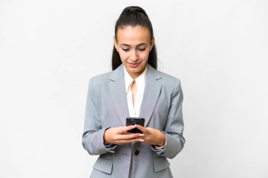 İzole edilmiş beyaz arka planda genç bir Arap kadın cep telefonuyla mesaj gönderiyor.
