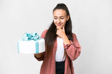 Genç Arap kadın, izole edilmiş beyaz arka planda doğum günü pastası tutuyor. Yan tarafa bakıyor ve gülümsüyor.