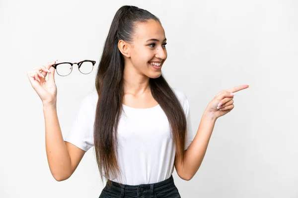 年轻的阿拉伯妇女将眼镜举过孤立的白色背景 指向侧面来展示一种产品 — 图库照片