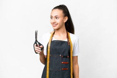 İzole edilmiş beyaz arka planda genç bir terzi kadın yana bakıyor ve gülümsüyor.