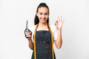 İzole edilmiş beyaz arka planda genç bir terzi kadın parmaklarıyla işaret veriyor.