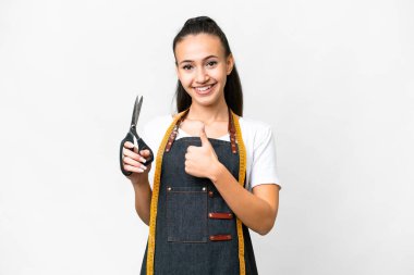 İzole edilmiş beyaz arka planda genç bir terzi kadın baş parmak hareketi yapıyor.