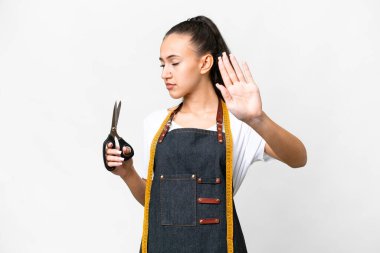 İzole edilmiş beyaz arka planda genç terzi kadın dur hareketi yapıyor ve hayal kırıklığına uğruyor.