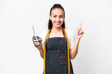 İzole edilmiş beyaz arka planda genç bir terzi kadın en iyinin işareti olarak parmağını kaldırıyor.