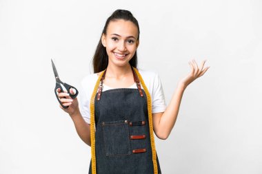 İzole edilmiş beyaz arka planda genç bir terzi kadın davet etmek için ellerini yana uzatıyor.
