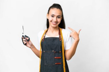 İzole edilmiş beyaz arka planda genç bir terzi kadın baş parmak hareketi yapıyor.