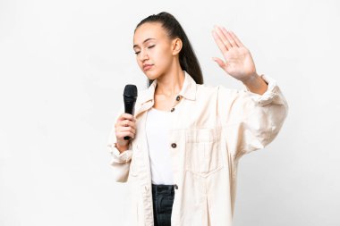Genç şarkıcı kadın, izole edilmiş beyaz arka planda mikrofonu eline aldı. Durma hareketi yaptı ve hayal kırıklığına uğradı.