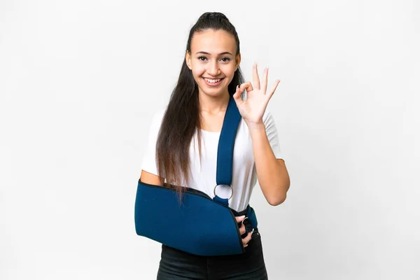 stock image Young Arabian woman with broken arm and wearing a sling over isolated white background showing ok sign with fingers