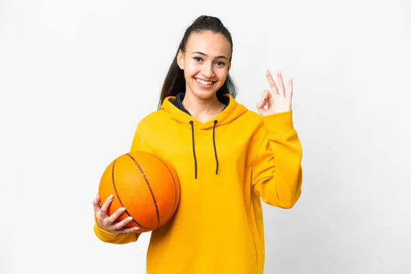 年轻的阿拉伯女子在孤独的白色背景上打篮球 手指显示出可控的标志 — 图库照片