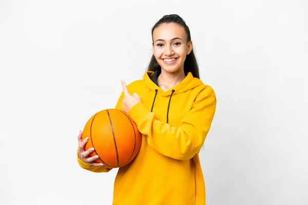 プロダクトを提示するために側面を指す隔離された白い背景の上にバスケットボールをしている若いアラビア人女性 — ストック写真