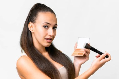 Makyaj paleti ile izole edilmiş beyaz arka planı olan genç bir Arap kadın.