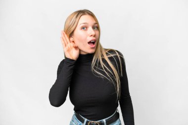Young pretty blonde woman over isolated white background listening to something by putting hand on the ear