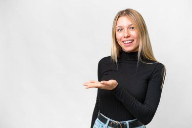 İzole edilmiş beyaz arka planda genç, güzel sarışın kadın gülümserken bir fikir sunuyor.