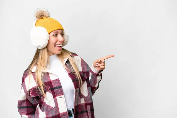 年轻漂亮的金发女人披着冬衣 罩在孤立的白色背景上 手指指向旁边 展示自己的产品 — 图库照片
