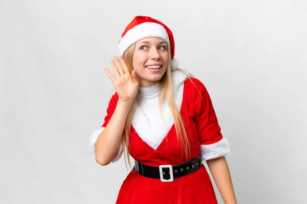 若いですブロンド女性とともにクリスマス帽子上の隔離された白い背景リッスン何かによって手を置くことによって耳 — ストック写真