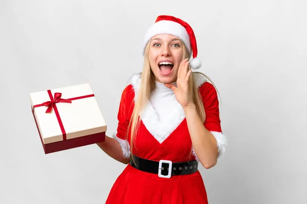 年轻的金发女人戴着圣诞礼帽 在孤零零的白色背景下举着礼物 张大嘴大喊 — 图库照片