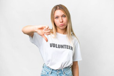 İzole edilmiş beyaz arka planda genç gönüllü kadın olumsuz ifade ile baş parmağını aşağı gösteriyor.