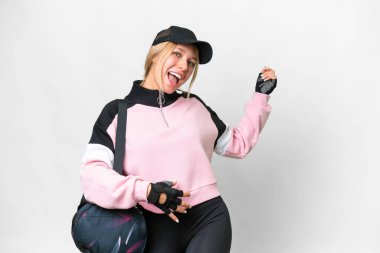 İzole edilmiş beyaz arka planda spor çantalı güzel bir kadın gitar hareketi yapıyor.