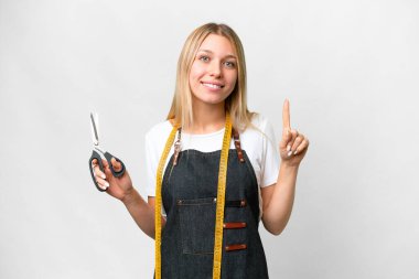 İzole edilmiş beyaz arka planı olan genç sarışın terzi kadın harika bir fikre işaret ediyor.