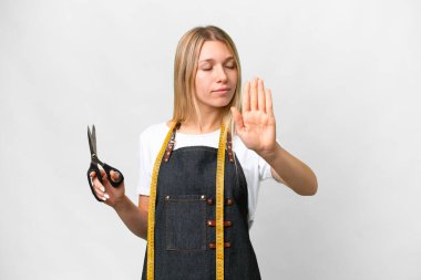 İzole edilmiş beyaz arka planda genç sarışın terzi kadın dur hareketi yapıyor ve hayal kırıklığına uğruyor.