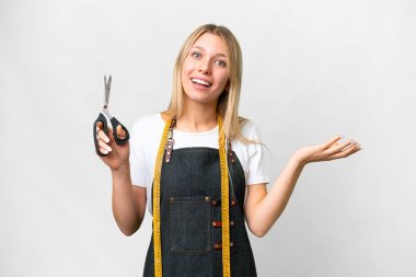 İzole edilmiş beyaz arka planda genç sarışın terzi kadın davet etmek için ellerini yana uzatıyor.