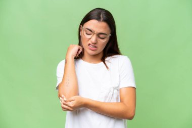 Genç beyaz kadın, yeşil krom arka planda izole edilmiş, dirsek ağrısı var.