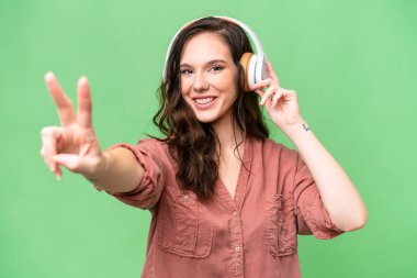 Young caucasian woman over isolated background listening music and singing