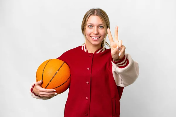 Молодая Блондинка Играет Баскетбол Изолированном Фоне Улыбаясь Показывая Знак Победы — стоковое фото
