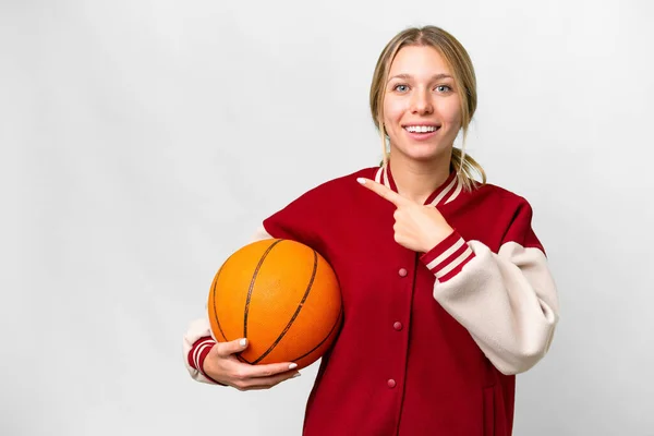 若いですブロンド女性遊びバスケットボール上の隔離された背景を指す側に製品を提示 — ストック写真