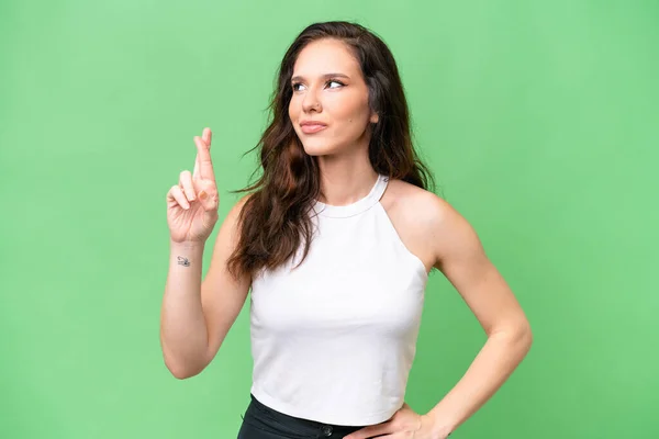 Young caucasian woman isolated over isolated background with fingers crossing and wishing the best