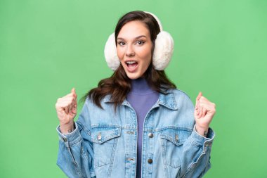 İzole edilmiş arka planda kışlık manşet takan beyaz bir kadın galibiyeti kutluyor.