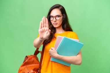 İzole edilmiş geçmişi olan beyaz bir genç kız dur hareketi yapıyor.