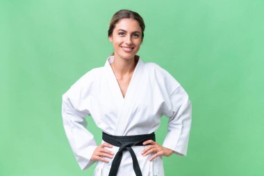 Genç Uruguaylı kadın karate yapıyor. Kollarını kalçasına dayayıp gülümsüyor.
