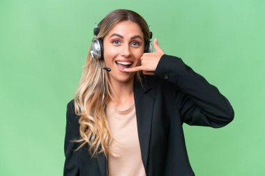 Tele pazarlamacı güzel Uruguaylı kadın izole edilmiş arka planda çalışan bir kulaklıkla telefon jesti yapıyor. Bana geri dönüş işareti ver.