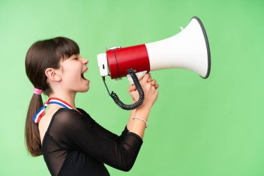 Tecrit edilmiş arka planda madalyaları olan beyaz bir kız megafondan bağırıyor.