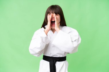 Kafkasyalı küçük bir kız tecrit edilmiş arka planda karate yapıyor bağırıyor ve bir şey duyuruyor.