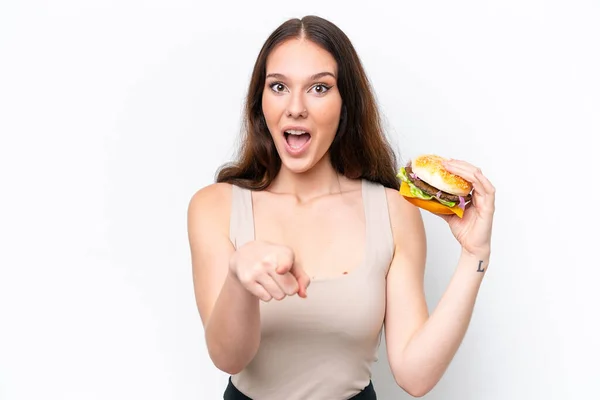 Mladá Běloška Drží Burger Izolované Bílém Pozadí Překvapen Ukazuje Dopředu — Stock fotografie
