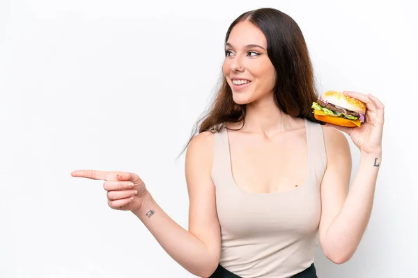 Молода Біла Жінка Тримає Бургер Ізольовано Білому Тлі Вказуючи Бік — стокове фото