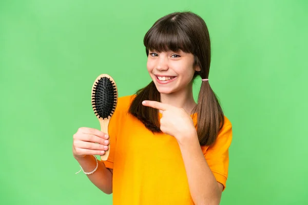 Little caucasian girl with hair comb over isolated background and pointing it