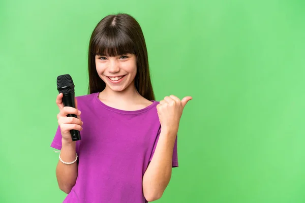 Little Singer Girl Picking Microphone Isolated Background Pointing Side Present — Stock Photo, Image