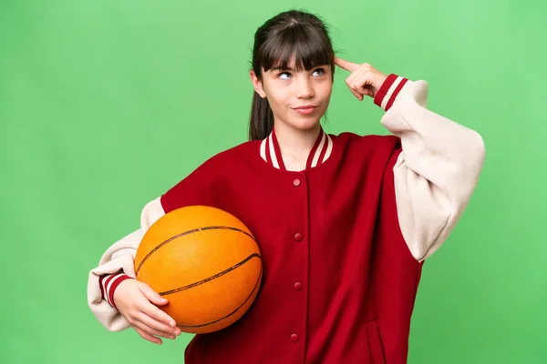 小さいですCaucasian女の子遊びバスケットボール上の隔離された背景を持っている疑問と考え — ストック写真