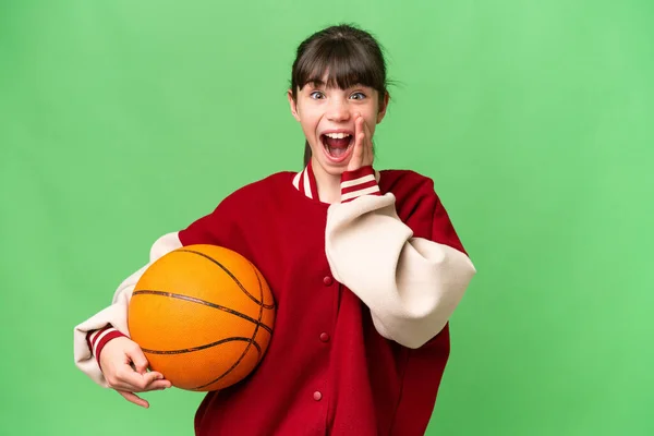 小さいですCaucasian女の子プレイバスケットボール上の隔離された背景とともに驚きとショックを受けた顔の式 — ストック写真